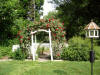 red climber Don Juan framing the entrance to a picket fenced rose garden